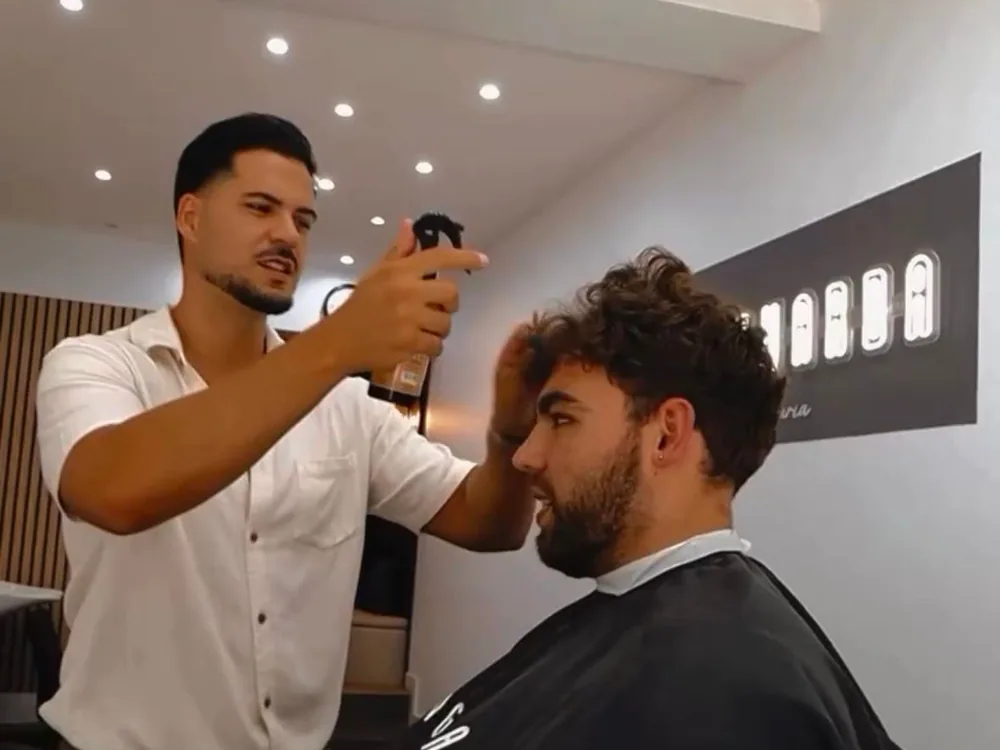 Barbeiro a dar o acabamento ao cabelo de um cliente